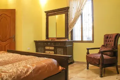 a bedroom with a dresser and a mirror and a chair at Khirfan Crown Houses -downtown in Amman