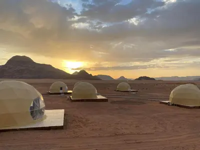 a group of tents in the desert with the sunset at Star rum in Wadi Rum