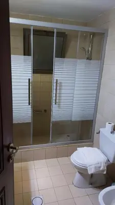 a bathroom with a glass shower and a toilet at Tala bay apartments 2 bedroom for family only in Aqaba