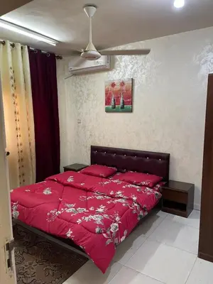 a bedroom with a red bed with red sheets at Abo Amer Apartments in Aqaba