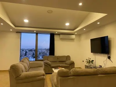a living room with two couches and a flat screen tv at The view IV in Amman