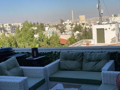 a couch on a balcony with a view of a city at The view II in Amman