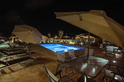 a swimming pool with chairs and umbrellas at night at Petra Seasons luxury Resort in Al Ḩayy