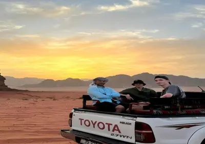 three men sitting in the back of a truck in the desert at Wadi rum stay in Wadi Rum