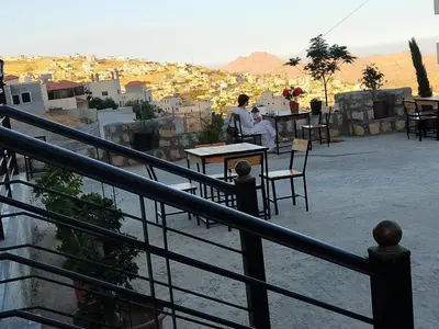 a man sitting at a table on a balcony overlooking a city at Treasury Terrace Apartments in Wadi Musa
