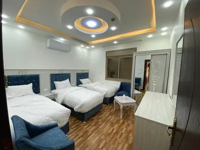 a hotel room with two beds and a blue chair at Treasury Terrace Apartments in Wadi Musa