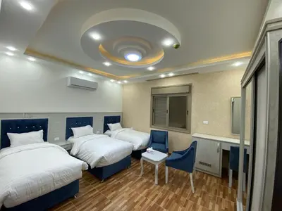 a hotel room with two beds and a table and chairs at Treasury Terrace Apartments in Wadi Musa