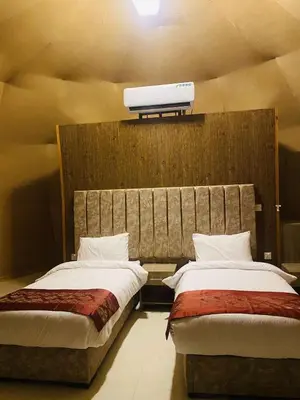 two beds in a room with a tv on the wall at WADi RUM LUXURY RITZ in Wadi Rum