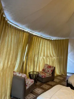 a bedroom with two chairs and a bed and a tent at WADi RUM LUXURY RITZ in Wadi Rum