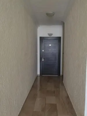 an empty hallway with a black door and a wooden floor at Dream Home in Amman
