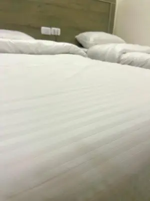 a close up of a bed with white sheets and pillows at RoadHouse - Petra in Wadi Musa