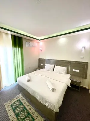 a bedroom with a large bed with white sheets and pillows at RoadHouse - Petra in Wadi Musa