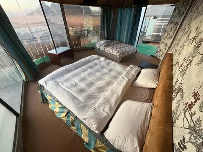 a large bed in a room with a large window at Al Raha Luxury Camp in Wadi Rum