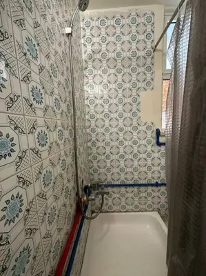 a bathroom with a tub and a tile wall at Antica old apartment al-lwebdeh in Amman