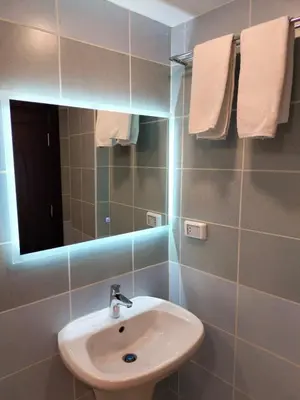 a bathroom with a sink and a mirror and towels at Old Street Apartment in Wadi Musa