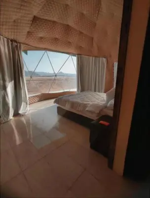 a bedroom with a bed and a large window at RUM ARJAAN lUXURY CAMP in Wadi Rum
