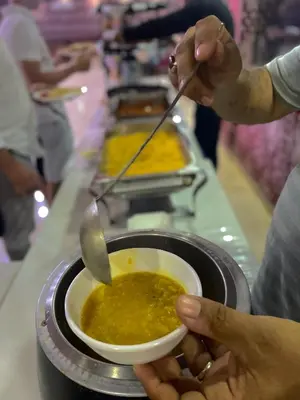 a person holding a bowl of food with a spoon at RUM ARJAAN lUXURY CAMP in Wadi Rum