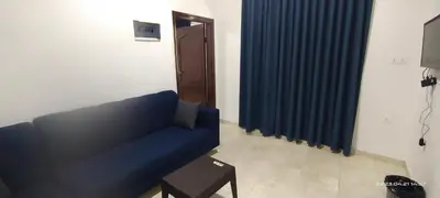 a blue couch in a living room with a blue curtain at Happy Beach For Studio Rooms Apartment شاطئ السعادة للشقق المفروشة in Aqaba