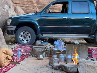 a blue truck parked in front of a campsite with a campfire at Wadi Rum stael Luxury Camp in Wadi Rum