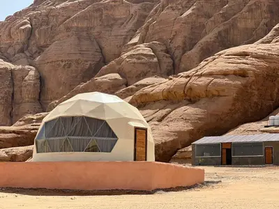 a building in the desert next to a mountain at Wadi Rum stael Luxury Camp in Wadi Rum