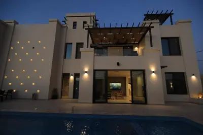a villa with a swimming pool at night at Zerø Føur DeadSea in Sowayma