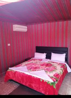 a bed in a room with a red wall at wadi rum Golden Sand in Wadi Rum