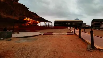a building with a fence in the middle of a dirt field at wadi rum Golden Sand in Wadi Rum