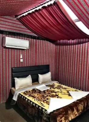 a bed in a room with a red wall at wadi rum Golden Sand in Wadi Rum
