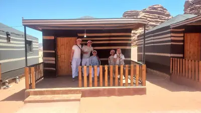 a group of people standing on the porch of a house at غرووب وادي رم in Wadi Rum
