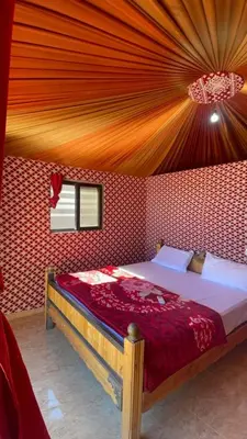 a bedroom with a large bed with a red wall at غرووب وادي رم in Wadi Rum