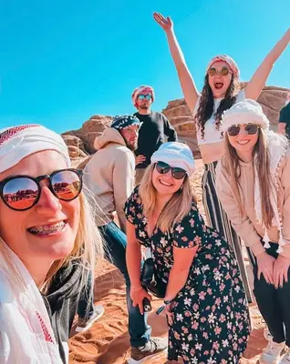 a group of people posing for a picture on the beach at Wadi Rum Red Sand Camp in Wadi Rum
