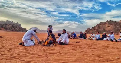 a group of people sitting around a fire in the desert at Wadi Rum Red Sand Camp in Wadi Rum