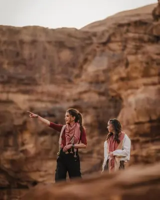 two women are standing in front of a mountain at Wadi rum sky luxury in Wadi Rum