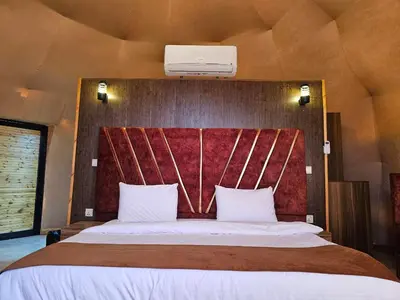 a bedroom with a large bed with a red headboard at Rand desert camp in Wadi Rum