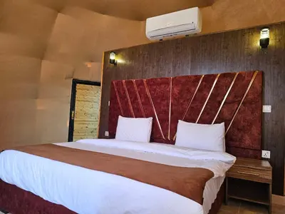 a bedroom with a large bed with a wooden headboard at Rand desert camp in Wadi Rum
