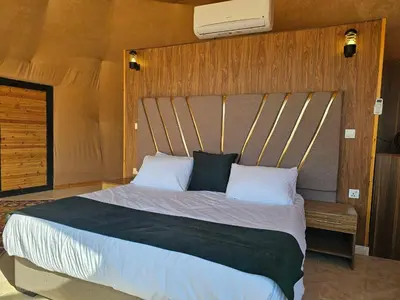 a bedroom with a large bed with a wooden headboard at Rand desert camp in Wadi Rum