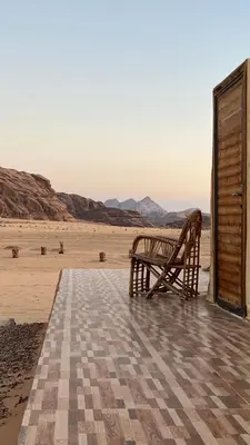 a wooden bench sitting on a porch overlooking the desert at Rum New Luxury Camp in Wadi Rum