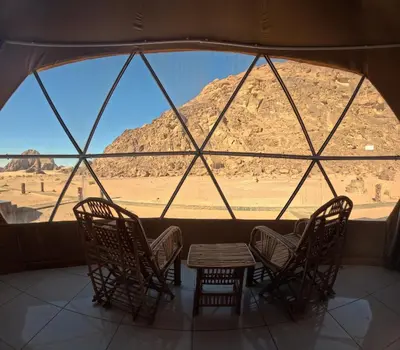 a room with chairs and a table and a view of the desert at Bedouin oasis in Wadi Rum