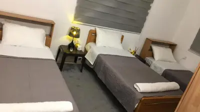 a bedroom with two beds and a table with a lamp at بيت العُمري (ام قيس) in Um Qeis