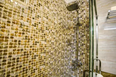 a bathroom with a shower with a tile wall at Dweik Hotel LUXURY 3 in Aqaba