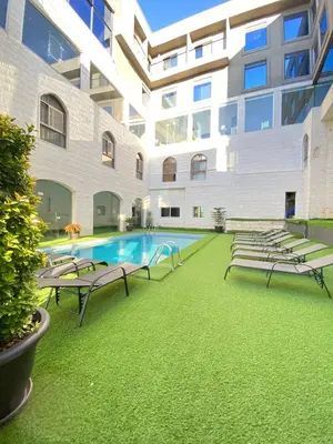 a large building with a swimming pool and benches at The RN Hotels in Wadi Musa