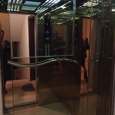 a glass door in a building with a man in the reflection at The Royal Luxury Tiger Patio in Amman
