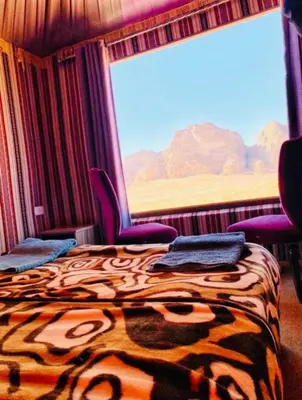a room with a bed and chairs and a large window at Wadi Rum Khalifa Camp in Wadi Rum