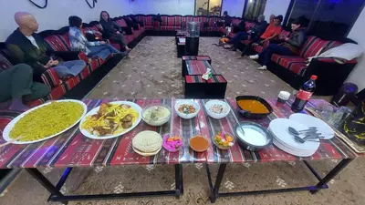 a table with plates of food on it with people at Wadi Rum Khalifa Camp in Wadi Rum