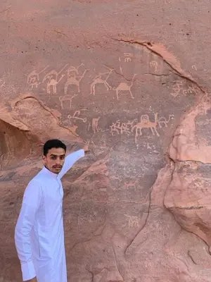 a man standing next to a rock wall with animals on it at Wadi Rum Khalifa Camp in Wadi Rum