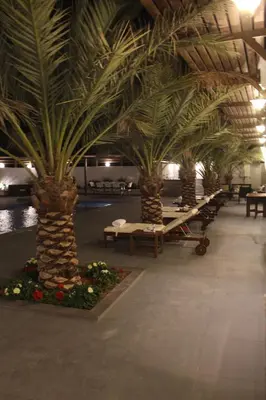 a row of palm trees in a building with tables at Golden rays chalet in Madaba