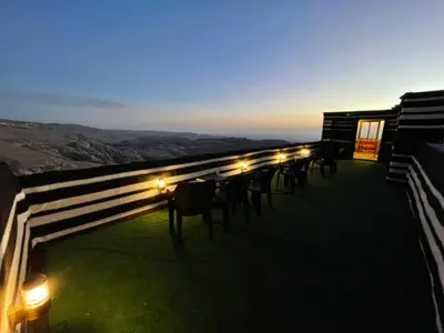 a row of tables and chairs on a roof with lights at Plaza View Hostel in Taiyiba