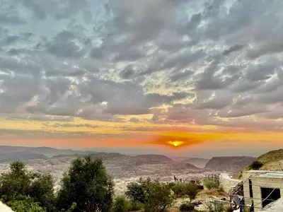 a sunset over the desert under a cloudy sky at Plaza View Hostel in Taiyiba