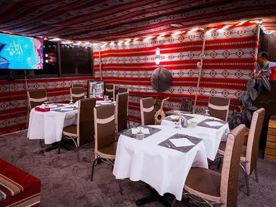 a restaurant with white tables and chairs and a screen at Plaza View Hostel in Taiyiba