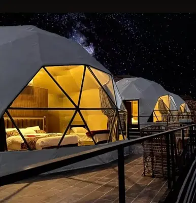 a group of tents on a deck at night at Wadi rum safari 1 camp in Wadi Rum